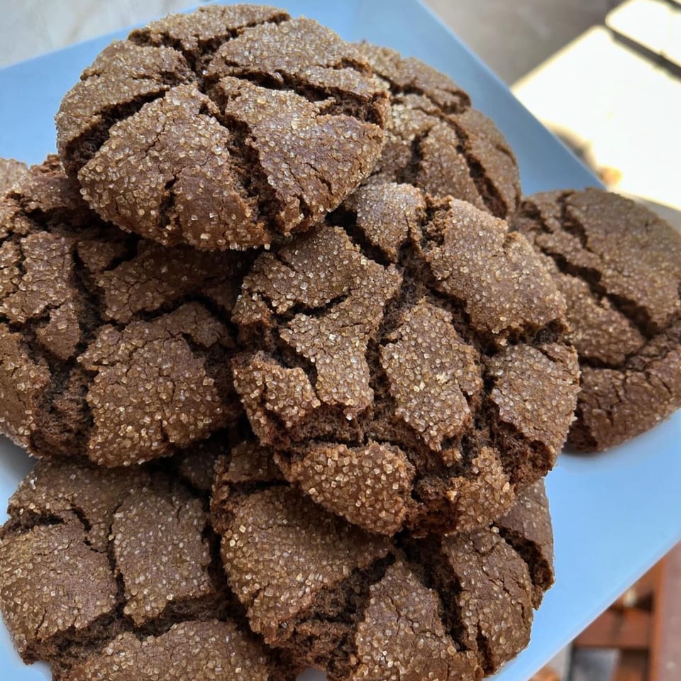 A close-up of several vegan chocolate crinkle cookies, generously coated with sparkling sugar.