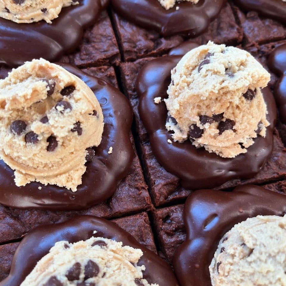 Close-up of vegan brownies topped with melted chocolate and scoops of cookie dough.